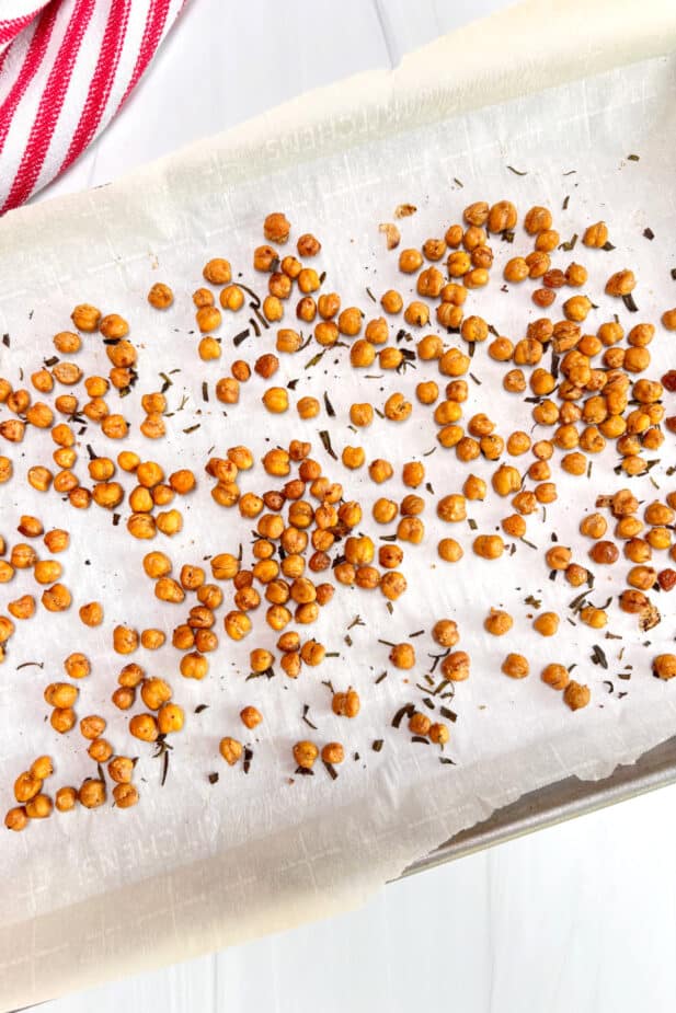 A parchment lined sheetpan with crispy oven roasted chickpeas and rosemary. 