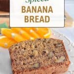 A slice of banana bread on a white plate with orange slices. A loaf of cut bread on a wood cutting board is in the background with a knife. The title, "Spiced Banana Bread" is in a light white box at the top of the picture.