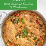A saute pan filled with cooked orzo, chicken breasts, sundried tomatoes, mushrooms and spinach garnished with fresh basil and pine nuts. It is sitting on a marble counter. The Title "Creamy Chicken with Orzo is in a bright green box on the top left of the picture.