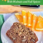 A slice of banana bread on a white plate with orange slices. A loaf of cut bread on a wood cutting board is in the background with a knife. "Spiced Banana Bread with Walnuts and Fall Spices" is at the top