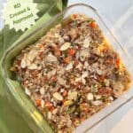A square glass casserole pan filled with brown and wild rice salmon casserole topped with crunchy almonds. RD Created and Approved is called out on the side.