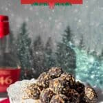A platter of bourbon balls coated in pecans with a bottle of bourbon overlooking a wintery scene in the backgound.