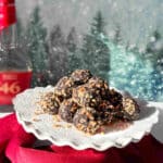 A platter of dark chocolate bourbon balls against a wintery scene with a bottle of high quality bourbon in the background.