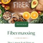 A wood board with the word "Fiber" in chalk in the middle surrounded by high fiber foods. Below is the Title: Fibermaxxing: The latest Fad Diet or something to Look into?