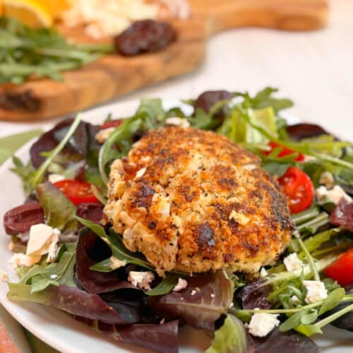 A salmon burger with canned salmon on top of a green salad