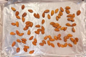 A pan of almonds coated in hot honey before putting them in the oven