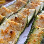 A white platter filled with strips of crispy parmesan coated zucchini