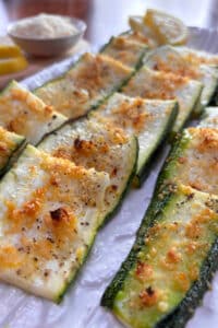 A white platter filled with strips of crispy parmesan coated zucchini