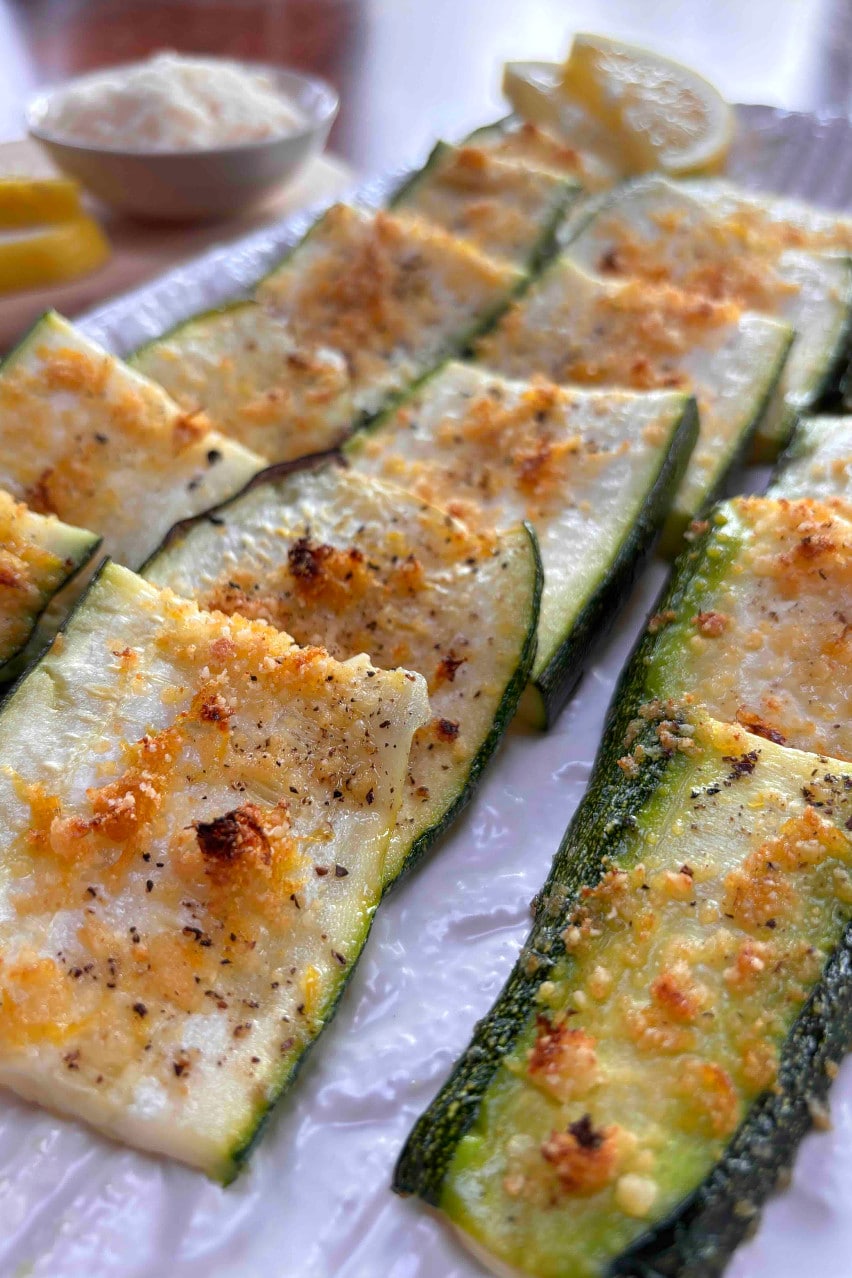 A white platter filled with strips of crispy parmesan coated zucchini