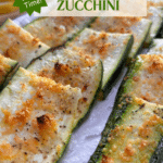 A platter filled with crispy zucchini strips with a bowl of parmesan cheese and lemon slices in the background. The title "Lemon Parmesan Roasted Zucchini" is at the top