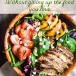 A wooden bowl filled with grilled peaches, vegetables and grilled chicken breast.